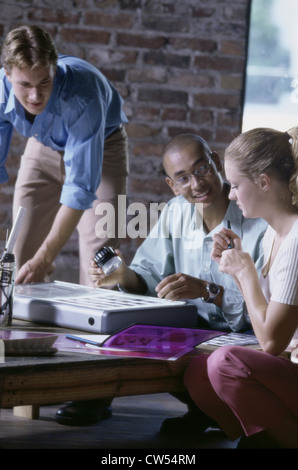 Two businessmen and a businesswoman working in an office Stock Photo