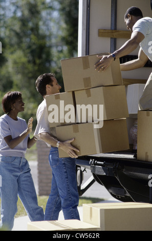 Mid adult couple unloading cardboard boxes from a moving van Stock Photo