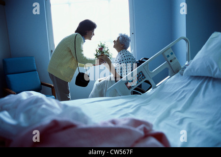 Mid adult woman giving flowers to a senior woman Stock Photo
