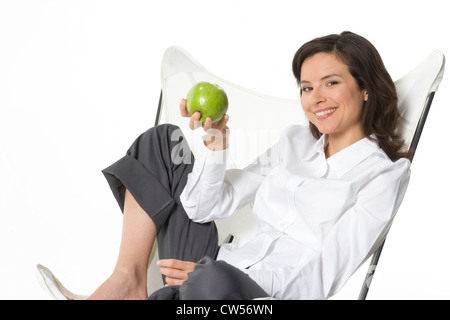 Young woman holding an apple and smiling Stock Photo