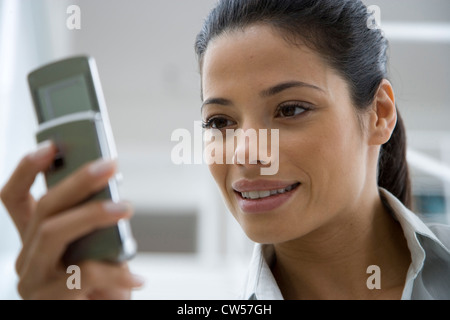 Close-up of a young woman looking at a mobile phone and smiling Stock Photo