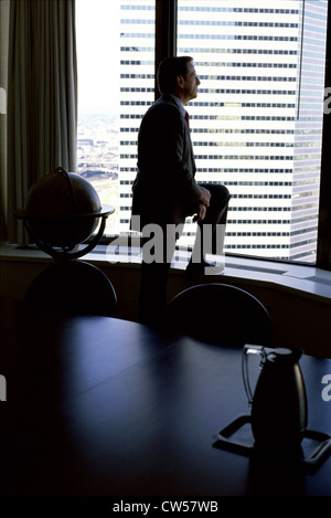 Businessman standing in a conference room and thinking Stock Photo
