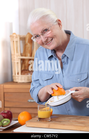 Elderly woman pouring freshly squeezed orange juice Stock Photo