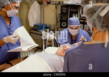 Three surgeons performing a surgery in an operating room Stock Photo