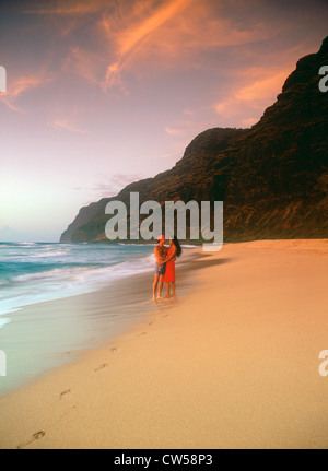 Couple embracing on Polihale Beach on Island of Kauai in Hawaii at sunset Stock Photo