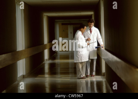 Two male doctors standing and talking to each other in a corridor Stock Photo