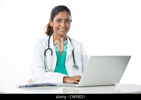 Female Asian doctor sitting at a table using a Laptop. Stock Photo
