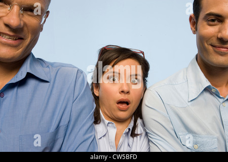Portrait of two businessmen smiling with a businesswoman making a face between them Stock Photo