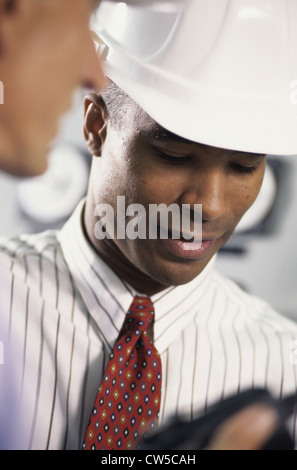 Young man wearing a hardhat looking down Stock Photo