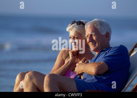 Senior couple sitting together in a chair and smiling Stock Photo