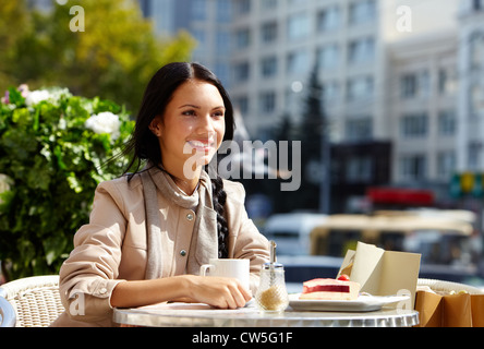 Image of happy female in open air cafe having coffee with cake in urban environment Stock Photo