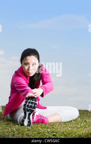 Chinese woman doing sit ups in park. Stock Photo