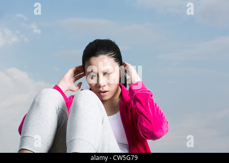 Chinese woman doing sit ups in park. Stock Photo