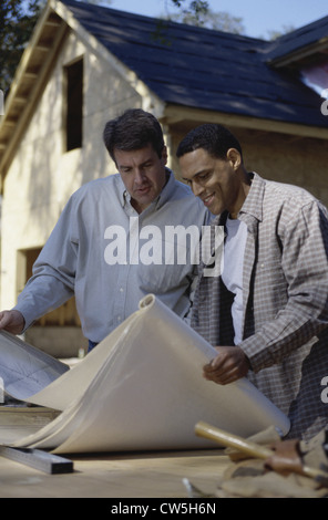 Two architects discussing blueprints at a construction site Stock Photo