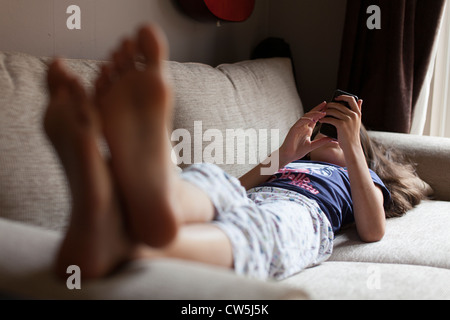 Young girl plays on mobile phone at home Stock Photo