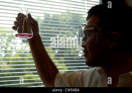 College student holding examining a solution in a conical flask in the chemistry lab class Stock Photo