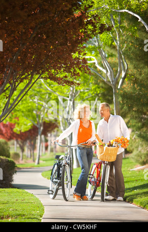 Senior couple walking with bicycles in a park Stock Photo