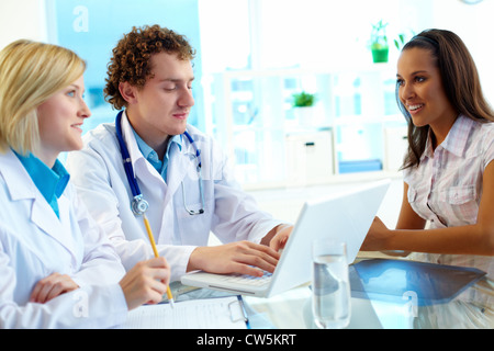 Portrait of confident practitioners and patient communicating in hospital Stock Photo