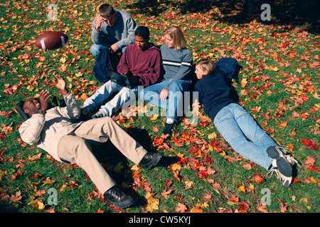 University students lying on grass and fallen leaves Stock Photo