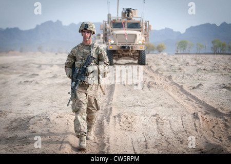 A US Army paratrooper returns to his base in Afghanistan's southern Ghazni province in front of a Mine Resistant Ambush Protected vehicle or MRAP April 8, 2012. His brigade took over the Polish mission in the area in early April. Stock Photo