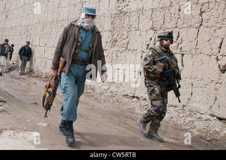 An Afghan policeman and French military policeman from joint forces patrol around compounds during their mission March 14, 2011 in Kabul, Afghanistan. Stock Photo