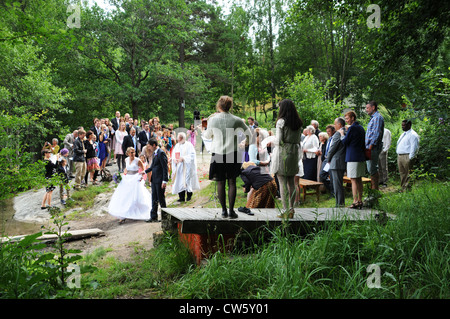 Wedding ceremonies with bride and groom and priest on shoreline of lake or Baltic Sea in Sweden Stock Photo