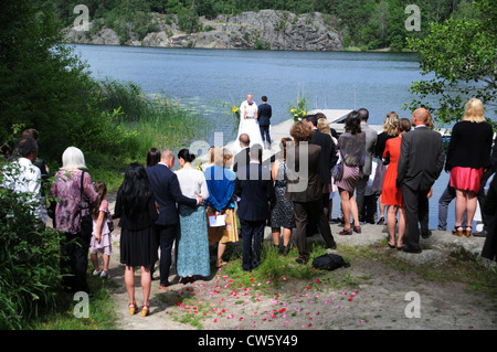 Wedding ceremonies with bride and groom and priest on shoreline of lake or Baltic Sea in Sweden Stock Photo