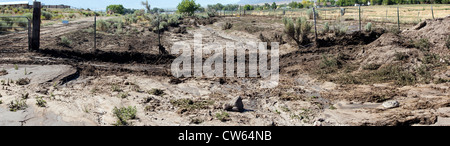 Flood after math showing where water came over a country road, mud and debri threaten farm fields.  Central Utah, summer. Stock Photo