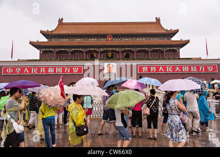 Tourists sheltering under umbrellas walk past the Gate of Heavenly Peace at the Forbidden City during a rainy in Beijing Stock Photo