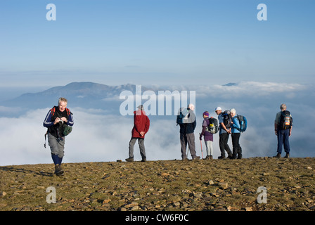 Group of walkers on the summit of Crag Hill, Lake District, looking down at the cloud. Stock Photo