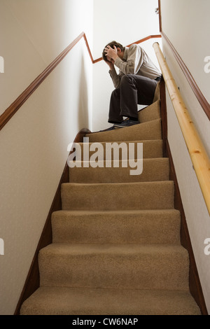 Man sitting on stairs, head in hands. Stock Photo