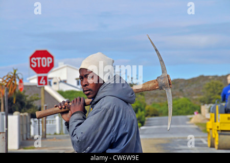 black roadworker with a pickaxe over the shoulder, South Africa, Arniston Stock Photo