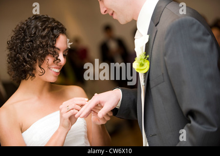 married in a civil ceremony, bride sticking the wedding ring at the finger of her husband Stock Photo