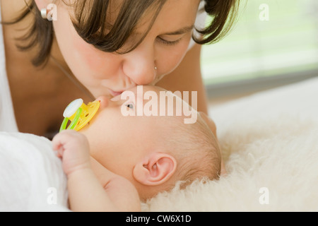 mother kissing her 1 month old baby on the brow Stock Photo