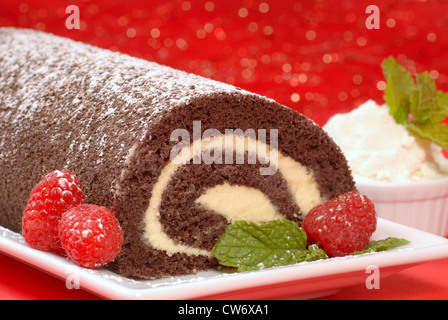Delicious Christmas Buche de Noel cake with raspberries, whipped cream and powdered sugar Stock Photo