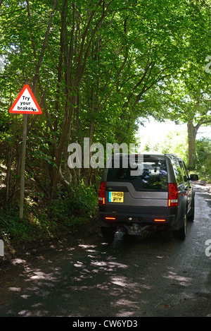 four wheel drive vehicle passing try your brakes warning sign after ford across road Bardsey Yorkshire UK Stock Photo