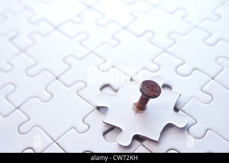 missing part of a puzzle fixed with a rusty screw Stock Photo