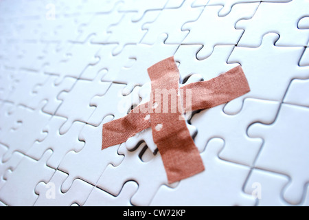 missing part of a puzzle fixed with a sticking plaster Stock Photo