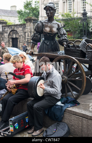 Dublin Ireland - Buskers at bronze statue of Molly Malone on Grafton Street, beside Trinity College, by sculptor Jeanne Rynhart. Stock Photo