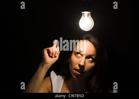 shining electric bulb over a young woman's head symbolising Stock Photo