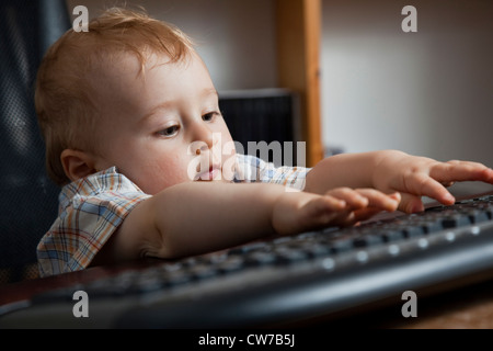 little, 10 months old boy in a swivel chair in an office Stock Photo
