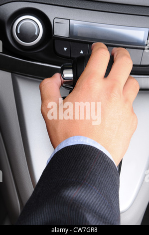 Closeup of a man's hand on the gear shifter of his car. Vertical Format. Man and car are unrecognizable. Stock Photo