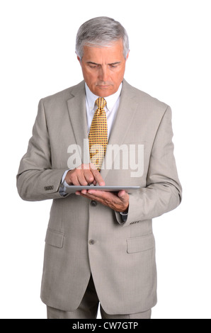 Middle aged businessman looking down at the tablet computer in his hands. Vertical format over a white background. Stock Photo