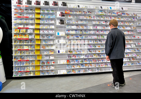 boy standing in front of a rack with electronic toys, Germany Stock Photo