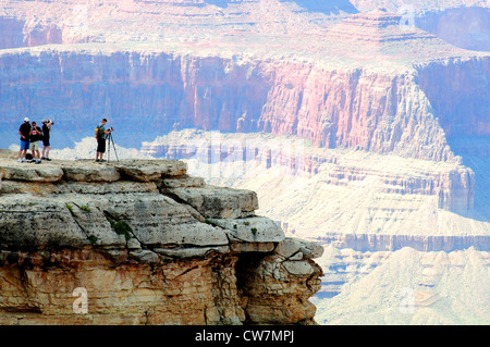 A photographer takes pictures from a rocky point overlooking the South Rim of the Grand Canyon Stock Photo
