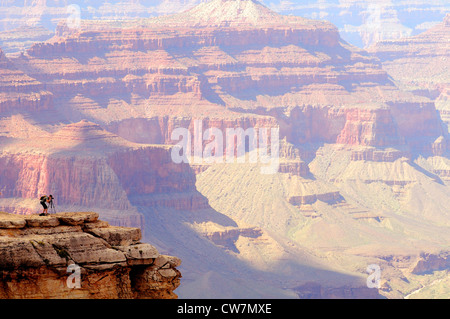 A photographer takes pictures from a rocky point overlooking the South Rim of the Grand Canyon Stock Photo