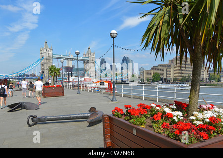 Thames path Butlers Wharf on River Thames views of Tower Bridge & London skyline waterside flower blooms in planter boxes & cordyline trees London UK Stock Photo