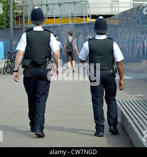 Back view of white & black policeman officer in summer traditional uniform & helmet on Metropolitan Police foot patrol in Southwark London England UK