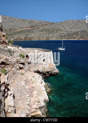 A  yacht sails past the fortifications on the northern side of the Venetian fort and former leper colony of Spinalonga,  Crete Stock Photo