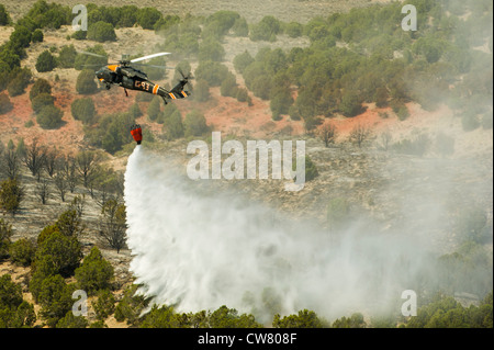 Utah National Guard Detachment 2, Company C, 1st General Support Aviation Battalion, 171st Aviation Regiment from West Jordan, Utah, performs water drops with a 'Bambi Bucket' onto a wildfire on Utah Training Center Camp Williams, Utah, 6 Aug. 2012. Bambi Buckets are a trademarked name for collapsible water buckets made by SEI Industries, a Canadian company. They can dump 660 of gallons of water on a fire at a time. Stock Photo